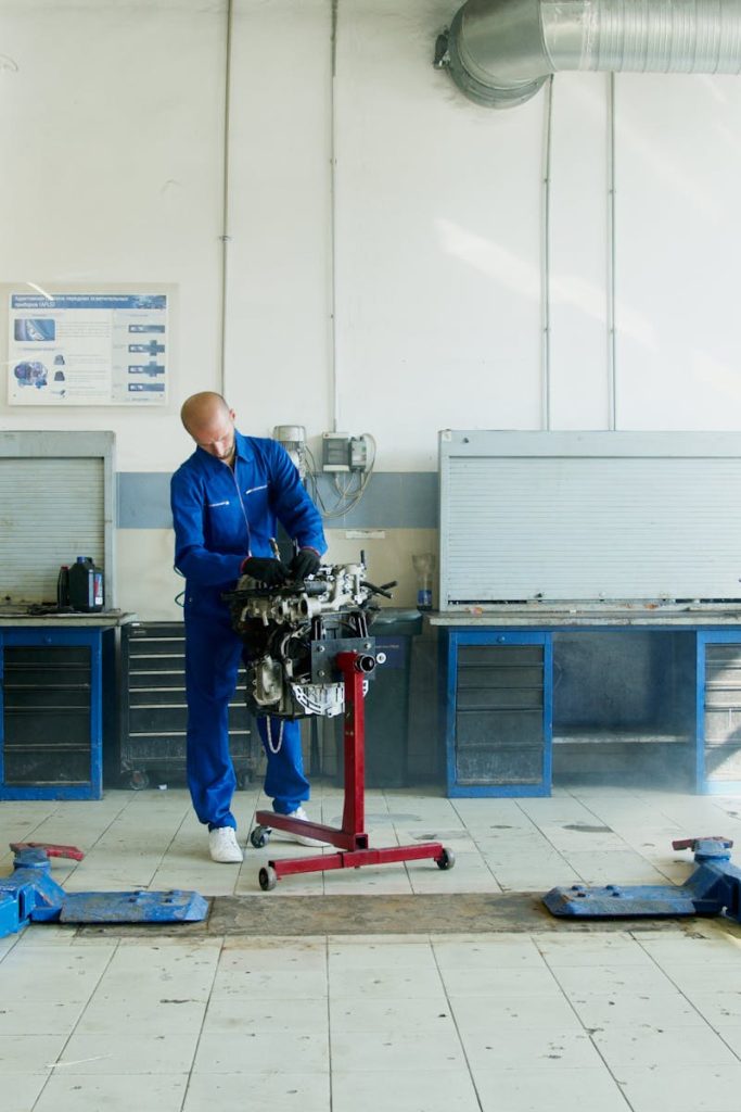 Mechanic inspecting car engine in well-equipped auto repair shop.